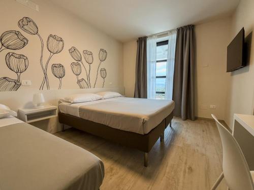 a bedroom with two beds and a window with flowers on the wall at Hurz in Pietrelcina