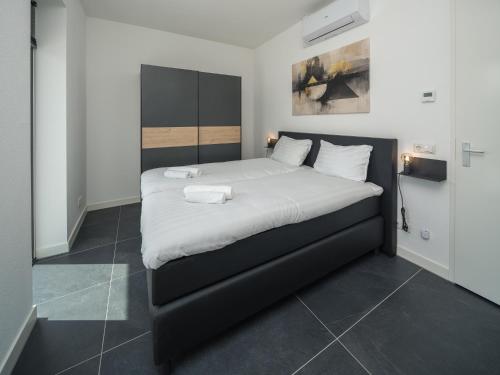 a bedroom with a large bed with white sheets at Harderwold Villa Resort in Zeewolde