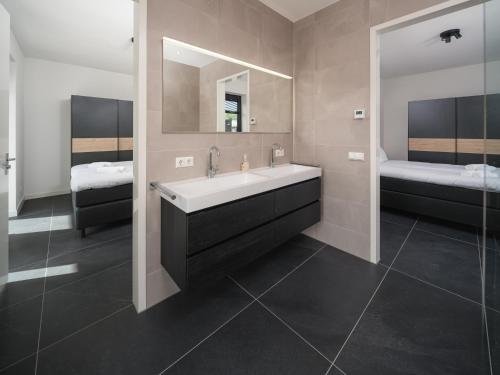 a bathroom with a sink and a mirror and two beds at Harderwold Villa Resort in Zeewolde
