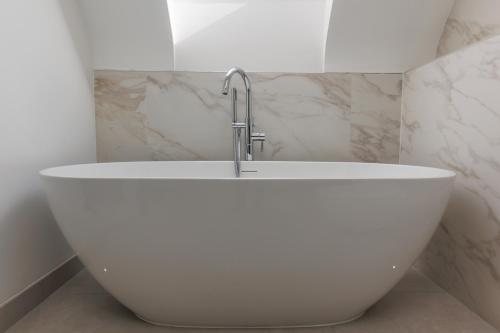 a white bath tub in a bathroom with a faucet at The Laurels by Grandeur Property in Poole