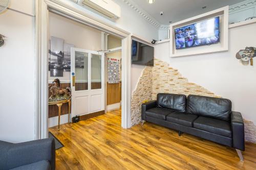 a living room with a couch and a tv on a wall at Linden House Hotel in London
