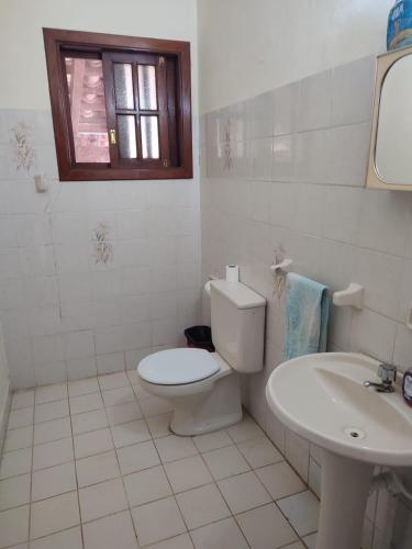 a white bathroom with a toilet and a sink at Gästehaus Samaipata in Samaipata