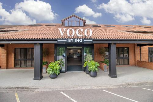 a building with two potted plants in front of it at voco Corby Kettering by IHG in Corby