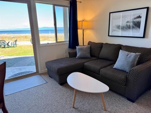 a living room with a couch and a table at Beachfront King Bed Studio Suite in Qualicum Beach