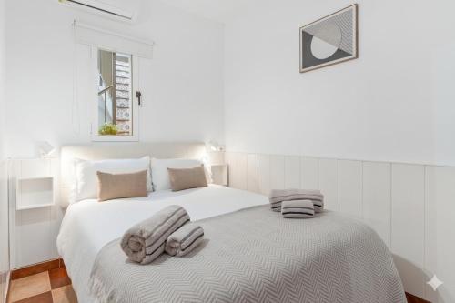 a white bedroom with two beds with towels on them at Casa Marbella in Fuengirola
