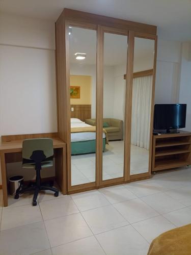 a room with a bedroom with a desk and a television at Flat Particular Marizienne Hotel Saint Moritz 86 in Brasília