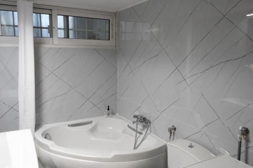 a white bathroom with a tub and a sink at Sea Breeze Alexandroupolis in Alexandroupoli