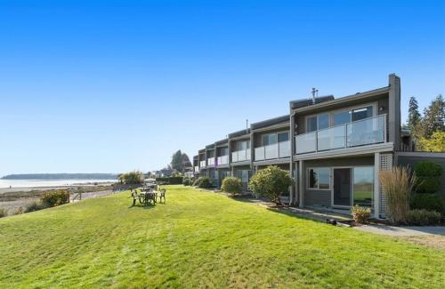 a house on a hill with a grassy yard at Oceanfront Studio with Loft - amazing views! in Qualicum Beach