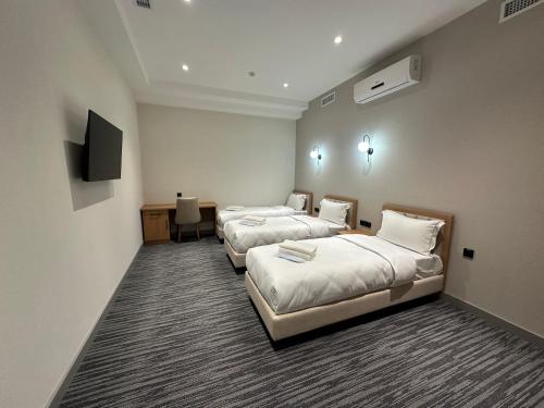 a hotel room with three beds and a television at Velnora Hotel in Tashkent