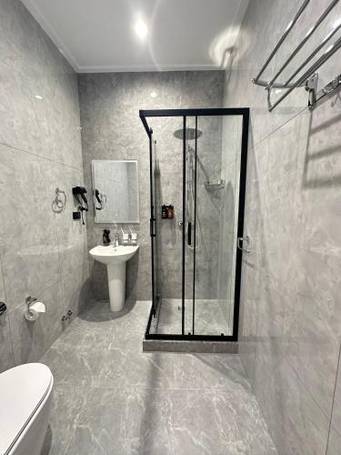 a bathroom with a shower and a toilet and a sink at Velnora Hotel in Tashkent