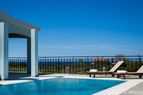a swimming pool with two chairs and a bench at Estrellas Luxury Villas in Svoronata