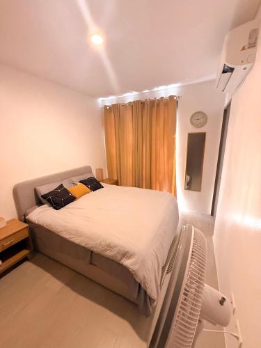 a small bedroom with a bed with white sheets at Enzos Haven - Tagaytay in Tagaytay