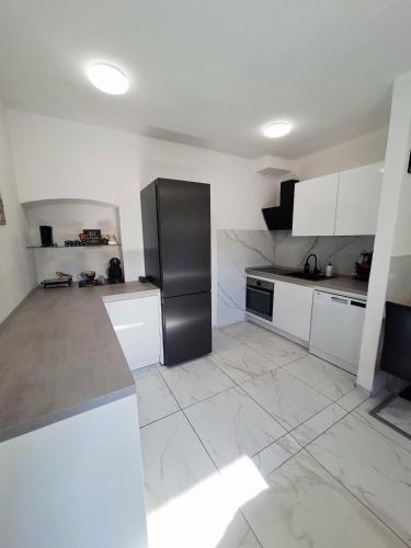 a kitchen with white cabinets and a black refrigerator at Casa D'oro1700 - Old town Koper in Koper