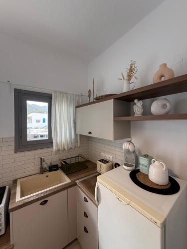 a small kitchen with white cabinets and a sink at Akti Rooms And Studios in Livadi
