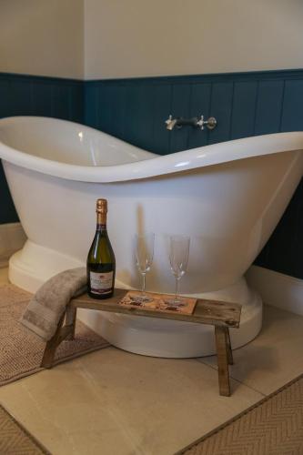 a white bath tub with two glasses and a bottle of wine at Windsor Cottage in Holmfirth