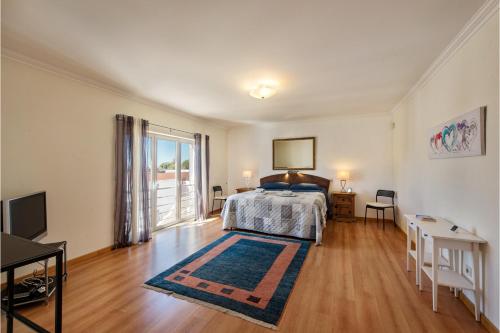 a bedroom with a bed and a large window at Casa Brisa Tavira in Tavira