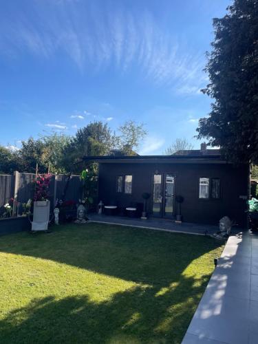 a small house in a yard with a lawn at Family cottage in Epsom