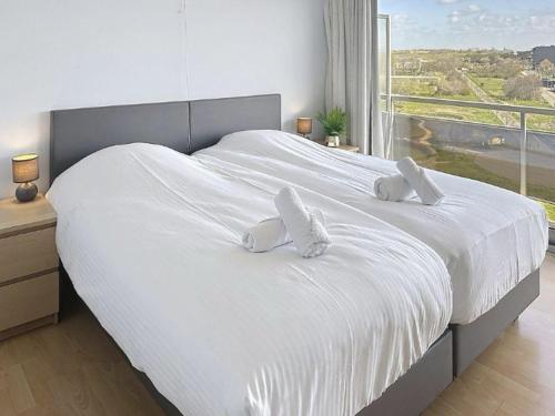 a white bed with two pillows on it with a window at Apartment Astrid 602 with balcony by Interhome in Bredene