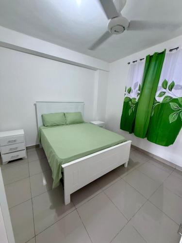 a white bedroom with a bed with green sheets at Aparta Hotel Mi Dulce Amanecer 2 in Cabrera
