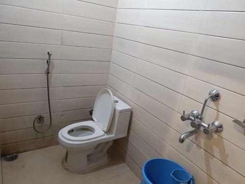 a bathroom with a toilet and a blue trash can at Hotel Sanwariya Palace in Haridwār