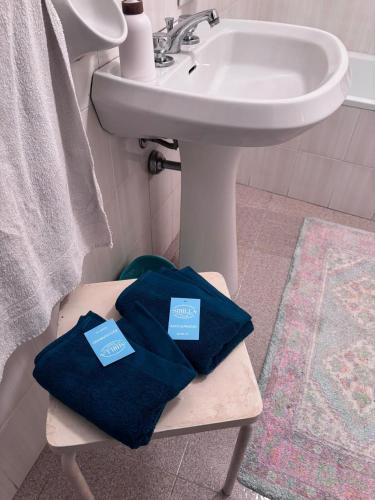 a bathroom with two blue towels on a stool next to a sink at Dai Nonni Vacation Home in Acciano