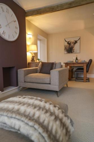 a living room with a couch and a clock on the wall at Windsor Cottage in Holmfirth