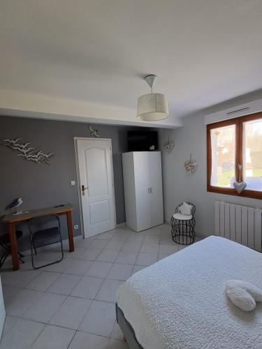a bedroom with a bed and a desk and a window at La salicorne in Pendé