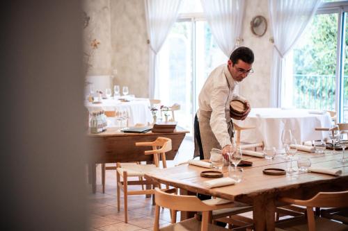 a man standing over a table in a restaurant at Logis Hôtel & Restaurant Le Cheval Blanc et Clovis in Vouillé