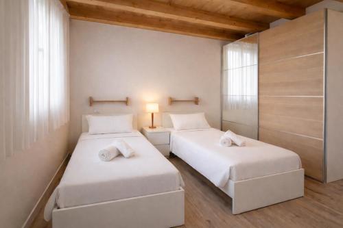 two beds in a room with white walls and wooden ceilings at Villa Alberti - Elegant, Spacious & Bright Villa in Casa Reali