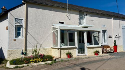 a white house with a large window and flowers at Chaintre La Ferme in Château-Chinon