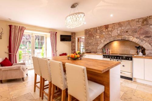 a kitchen with a wooden table and a stone wall at The Old Mill House Experience in Dalkeith