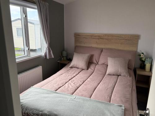 a bed with a pink comforter in a bedroom at Shivvys at sandylands in Stevenston