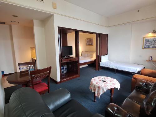 a hotel room with a couch and a bed and a table at Sunshine Suites Times square KL in Kuala Lumpur
