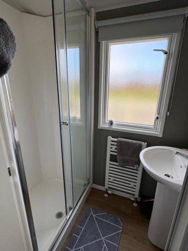 a bathroom with a shower and a sink and a window at Shivvys at sandylands in Stevenston