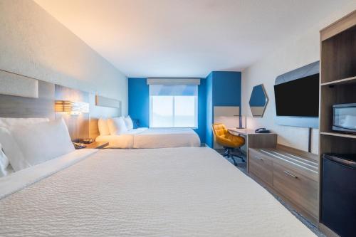 a hotel room with two beds and a flat screen tv at Holiday Inn Express & Suites Kansas City Airport by IHG in Kansas City