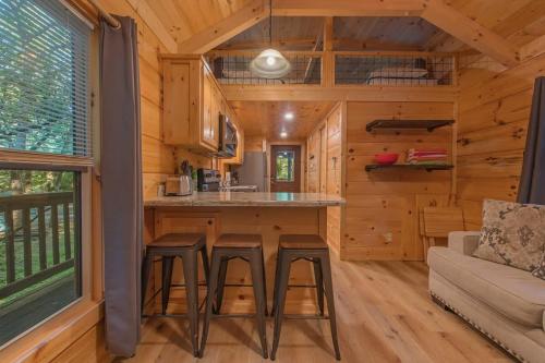 a log cabin kitchen with a couch and stools at Celina Cabin Nature Cabin Near Downtown Chattanooga in Chattanooga