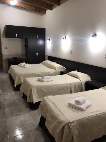 a room with three beds with towels on them at Hotel Avenida in General Alvear