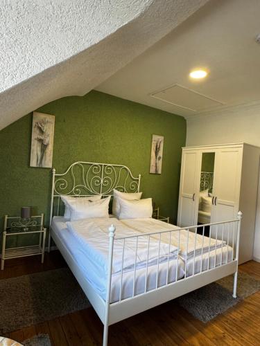 a bedroom with a white bed with a green wall at Gästehaus Flair in Mettlach