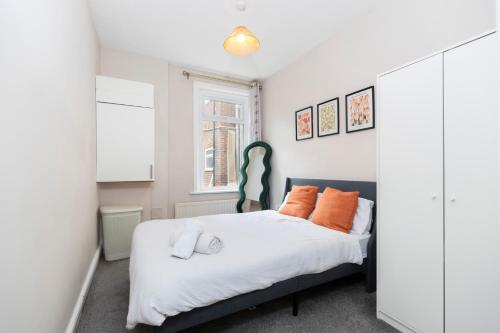 a bedroom with a bed with orange pillows at Bright & Comfortable 2-Bed Home 5 mins from Newcastle City Centre - Free Parking in Gateshead