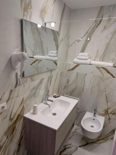 a bathroom with a sink and a toilet and a mirror at Saraceno House G&P in Adrano
