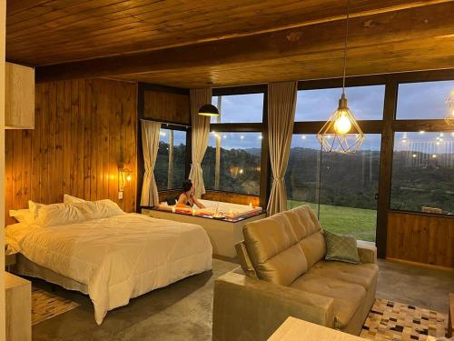 a bedroom with a bed and a living room with a couch at Cabanas Monte Belo in Santa Cruz do Sul