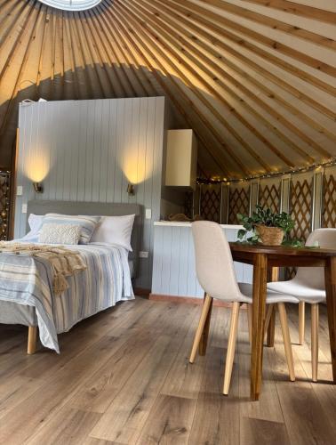 a bedroom with a bed and a wooden table at Yurts at Yelverton in Yelverton