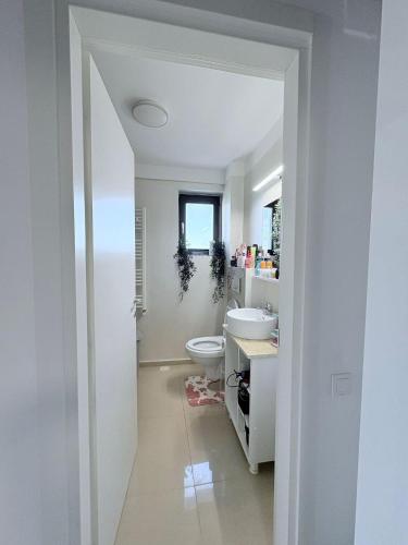 a white bathroom with a toilet and a sink at Tower Apartments A6 in Năvodari