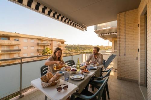 a man and a woman sitting at a table on a balcony at Mediterranean Way - Maldivas in La Pineda