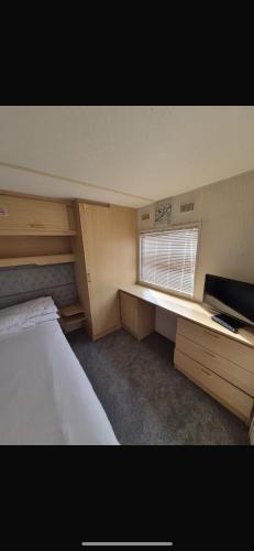 a bedroom with a bed and a desk and a window at Coastal Getaway, camber sands in Camber