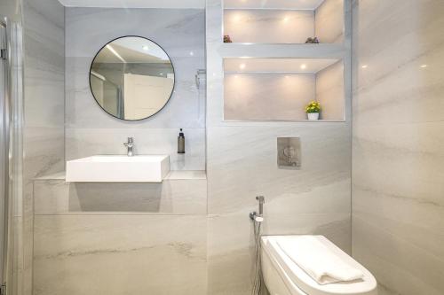 a white bathroom with a sink and a mirror at Linden House Hotel in London