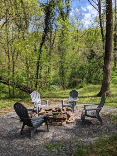 three chairs and a fire pit in a park at Peggers Cabin Luxury Rustic Tiny Cabin Spa in Chattanooga