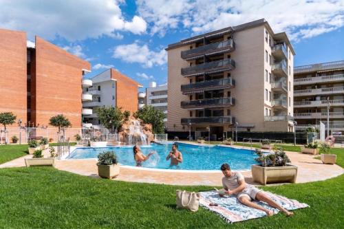 a group of people laying in the grass by a swimming pool at Mediterranean Way - Maldivas in La Pineda