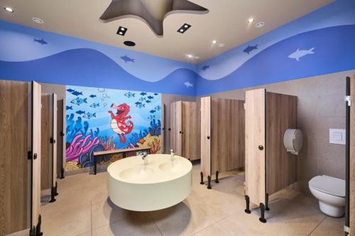 a bathroom with a tub and a toilet and a mural at SUNNY Mobile Homes Bijela Uvala in Poreč