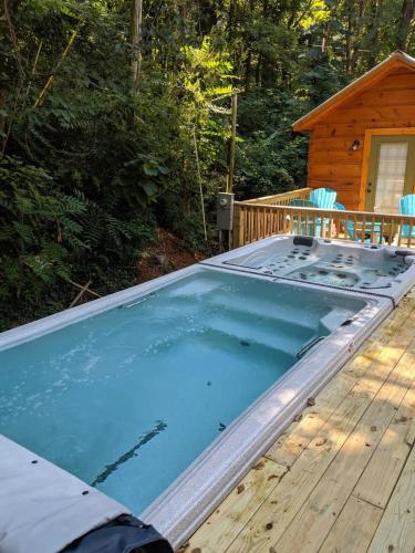 a large swimming pool on a deck with a cabin at River Cabin Hot Tub & Swim Spa Near Downtown in Chattanooga